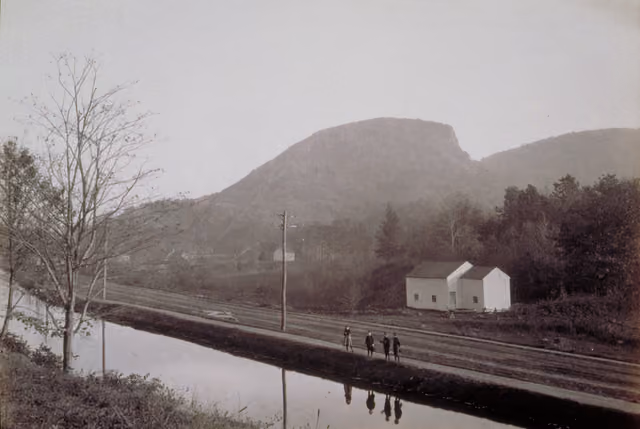 A girl and three boys stand on a dirt path between a canal and a dirt road — Sleeping Giant State Park